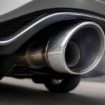 Zbliżenie na metalową końcówkę wydechu sportowego samochodu z widoczną parą spalin