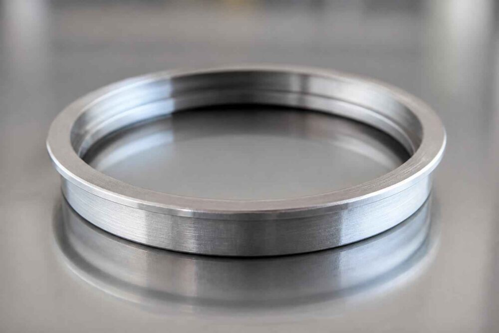 Srebrny metalowy pierścień leżący na błyszczącej stalowej powierzchni
