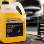 Kanister płynu chłodniczego Renault stojący przy otwartej masce i narzędziach warsztatowych