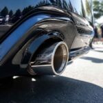 Zbliżenie na chromowaną końcówkę wydechu czarnego samochodu sportowego podczas plenerowego wydarzenia motoryzacyjnego