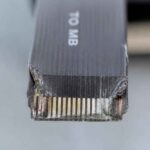 Zbliżenie uszkodzonej wtyczki kabla Ethernet z widocznymi stykami i napisem Cat 6a