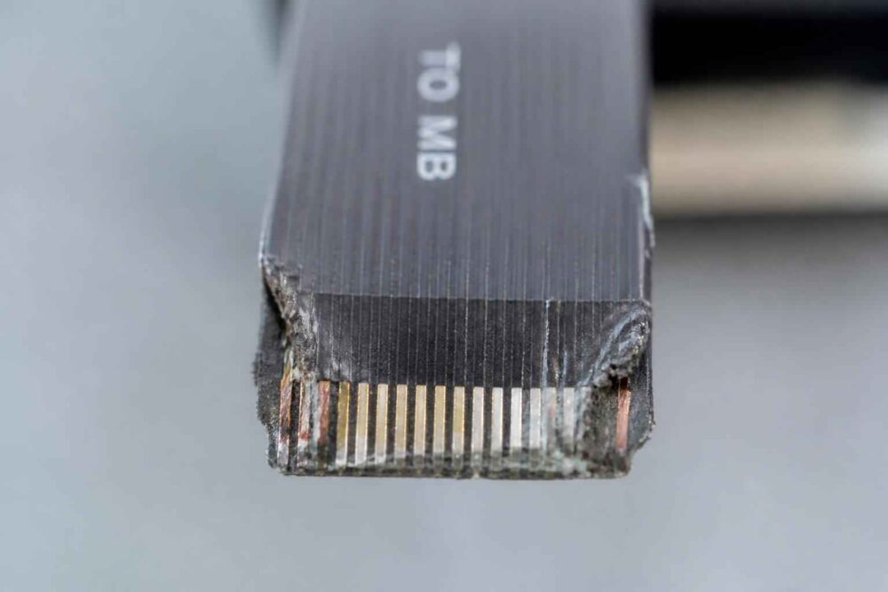 Zbliżenie uszkodzonej wtyczki kabla Ethernet z widocznymi stykami i napisem Cat 6a