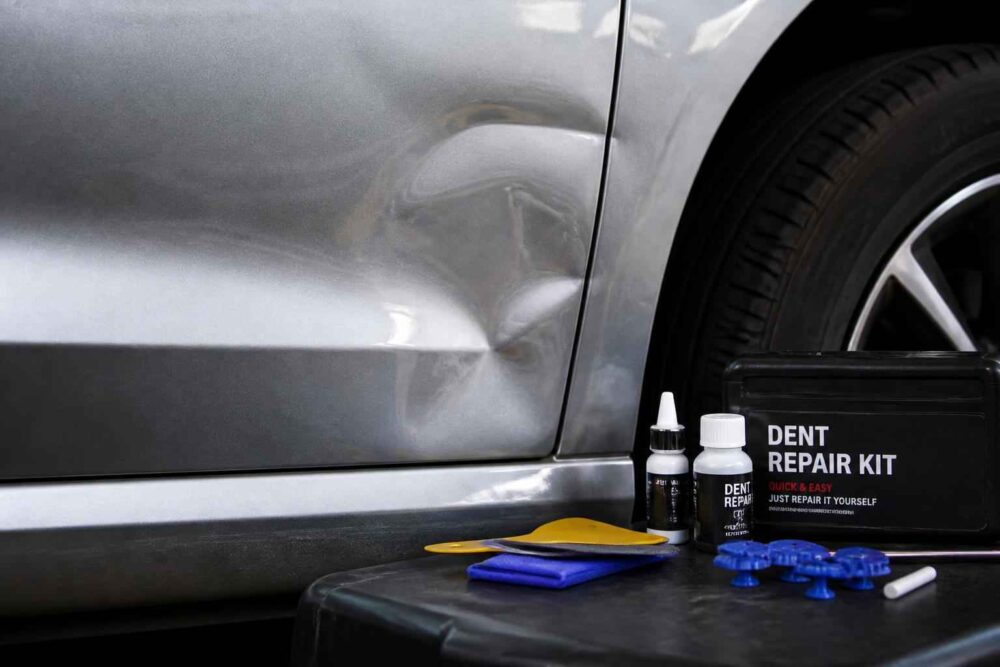 Zestaw Dent Repair Kit ustawiony obok wgniecionych drzwi samochodu